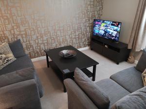 uma sala de estar com um sofá, uma mesa e uma televisão em The Hedgehogs em Inverness