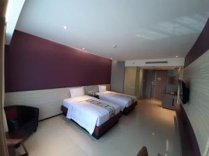 a bedroom with two beds and a purple wall at Hotel Asri Sumedang in Sumedang