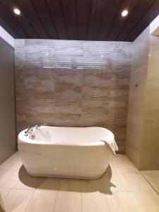 a white bath tub in a bathroom with a wall at Hotel Asri Sumedang in Sumedang