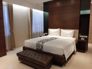 a bedroom with a large bed with a wooden headboard at Hotel Asri Sumedang in Sumedang
