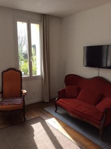 a living room with a red couch and a television at Aliénor in Bordeaux