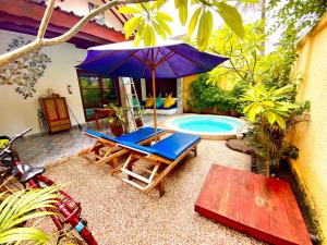 een patio met een stoel, een parasol en een zwembad bij Cinta Cottages in Gili Trawangan