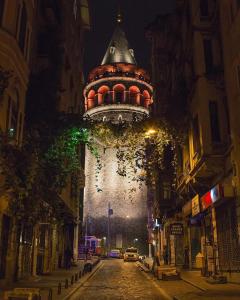 uma torre do relógio numa rua da cidade à noite em Royal Galata Hotel em Istambul