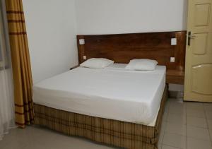 a bedroom with a white bed with a wooden headboard at iléos, appartement meublé 4 pièces - Salon, cuisine, 3 chambres Lomé Tokoin Hôpital Protestant in Lomé