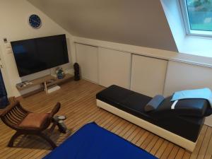 a living room with a couch and a chair and a flat screen tv at LOGEMENT ATYPIQUE BIEN ETRE AU CŒUR DE LA NATURE in Quimper