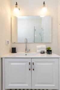 a white bathroom with a sink and a mirror at Arlozorov by TLV2RENT in Tel Aviv