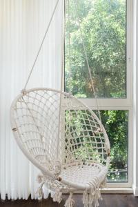 a white swinging chair in front of a window at Arlozorov by TLV2RENT in Tel Aviv