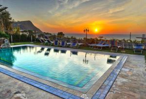 a swimming pool with a sunset in the background at Hotel Villa Cimmentorosso in Ischia