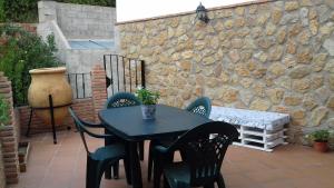 einen Tisch und Stühle auf einer Terrasse mit einer Steinmauer in der Unterkunft Casa Rural Las Nogueras in Caserío Arroyofrío