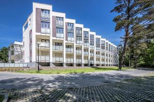 a large white building with a tree in front of it at TriApart Amber Jantar III in Jantar