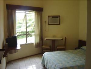 um quarto com uma cama, um lavatório e uma janela em Hotel Veleiro em Florianópolis
