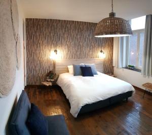 um quarto com uma grande cama branca e um sofá em Anthos B&B em Maaseik