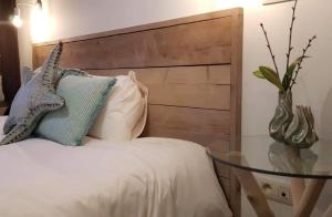 een bed met een houten hoofdeinde en een glazen tafel bij Anthos B&B in Maaseik
