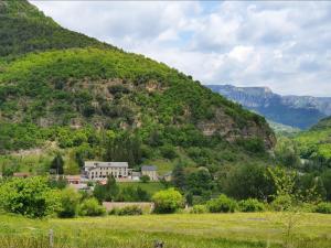 ein Haus mitten auf einem Feld vor einem Berg in der Unterkunft Hotel des Gorges au Viaduc in Rivière-sur-Tarn