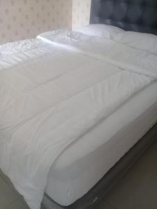 a bed with white sheets and pillows on it at Brand new and sweet @ apartemen parahyangan residence bandung in Bandung