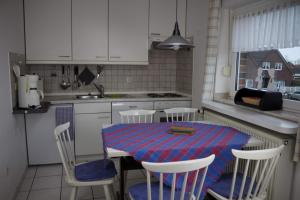 een keuken met een tafel en stoelen en een keuken met witte kasten bij FeWo Heitkamp in Dornumersiel