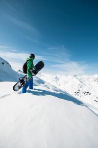 a person holding a snowboard on a snow covered mountain at Hotel Garni Maximilian in Zell am Ziller +14 photos