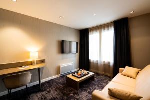 um quarto de hotel com um sofá e uma mesa em Fac & Spera -Hôtel & Spa em Tain-lʼHermitage