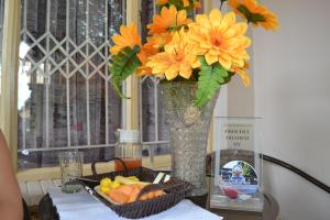 a vase with flowers and a basket of fruit on a table at Kamogelo Guest House in Pilanesberg
