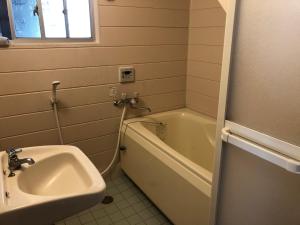 La salle de bains est pourvue d'un lavabo et d'une baignoire. dans l'établissement ゲストハウスAmaなつ, à Amami