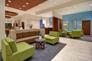 een lobby met groene stoelen en een bank en tafels bij Holiday Inn Express & Suites - Galveston Beach, an IHG Hotel in Galveston