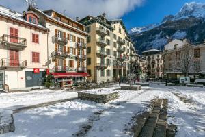 a snow covered street in a city with buildings at Hotel Le Chamonix in Chamonix-Mont-Blanc