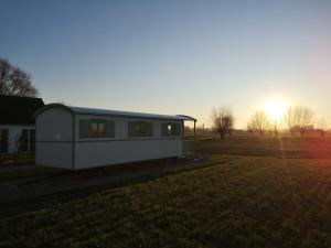 a house sitting on top of a grass field at Roulotte Hartemeers in Tielt