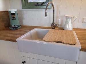 a kitchen sink with a cutting board in it at Roulotte Hartemeers in Tielt