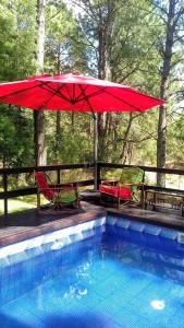 a red umbrella and two chairs and a swimming pool at Pelicano Carilo in Carilo