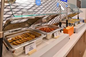 a buffet line with trays of food on a counter at Holiday Inn Express & Suites - Galveston Beach, an IHG Hotel in Galveston