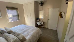 una camera da letto con un letto, una scrivania e una finestra di Maitlands Cottage a Port Elizabeth