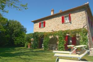 een stenen huis met rode luiken en een bank bij Holiday apartments La Bozza and Il Bozzino in Cortona