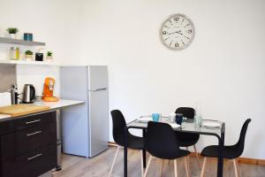 een keuken met een tafel en stoelen en een klok aan de muur bij Appartements cosy Audincourt - direct-renting ''renting with good vibes'' in Audincourt