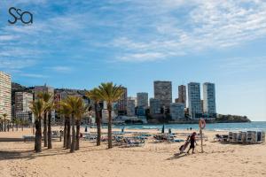 osoba spacerująca po plaży z palmami w obiekcie My Sweet Red Apartment w mieście Benidorm