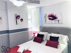 sypialnia z białym łóżkiem z czerwonymi i czarnymi poduszkami w obiekcie My Sweet Red Apartment w mieście Benidorm