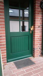 a green door on a brick building with a window at Apartement in Siedlung Schönwalde