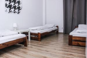 a room with three beds and a table at Baba Hostel in Kalisz