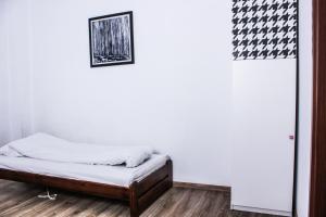 Cama en habitación con pared blanca en Baba Hostel, en Kalisz