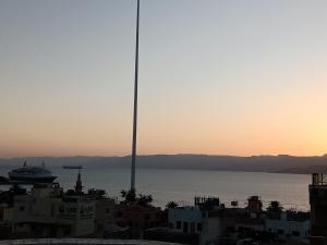 a view of the ocean at sunset with a cruise ship at seven7days hotel in Aqaba