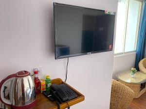 TV colgada en una pared con teléfono y cafetera en HOTEL ARMS near SUMI Boys School en Kalimpong