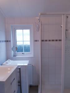 uma casa de banho branca com um lavatório e um chuveiro em Zeepark Haerendyke em De Haan