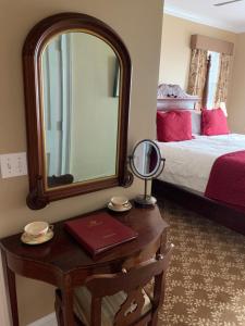 Almondy Inn Bed & Breakfast في نيوبورت: غرفة نوم مع مرآة وطاولة مع سرير