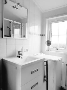 a white bathroom with a sink and a mirror at Zeepark Haerendyke in De Haan