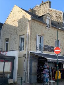 un edificio con un cartello stradale di fronte a un negozio di Appartement 3 Pièces Bord de mer Place du 6 Juin ad Arromanches-les-Bains