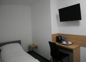 a room with a bed and a desk with a television at Alda Gold in Pyrzowice