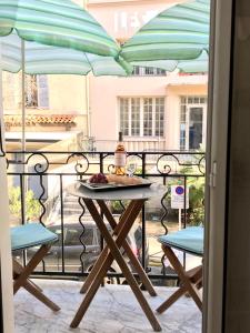 een tafel en stoelen op een balkon met een parasol bij Market in Antibes