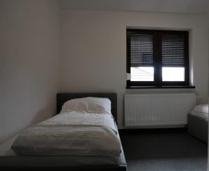 niewielka sypialnia z łóżkiem i oknem w obiekcie Alda Gold w Pyrzowicach