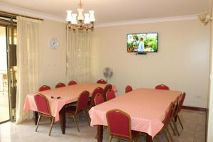 a dining room with two tables and chairs and a tv at Apricot Guest House Annex in Muyenga 