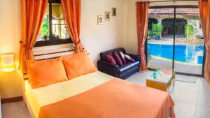 a bedroom with a bed and a chair and a pool at Coconut Paradise Villas in Rawai Beach