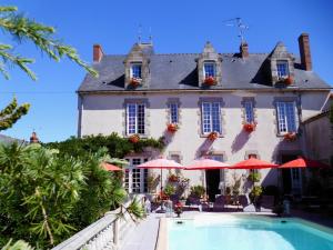 a hotel with a swimming pool in front of a building at Le Petit Château TIFFAUGES in Tiffauges